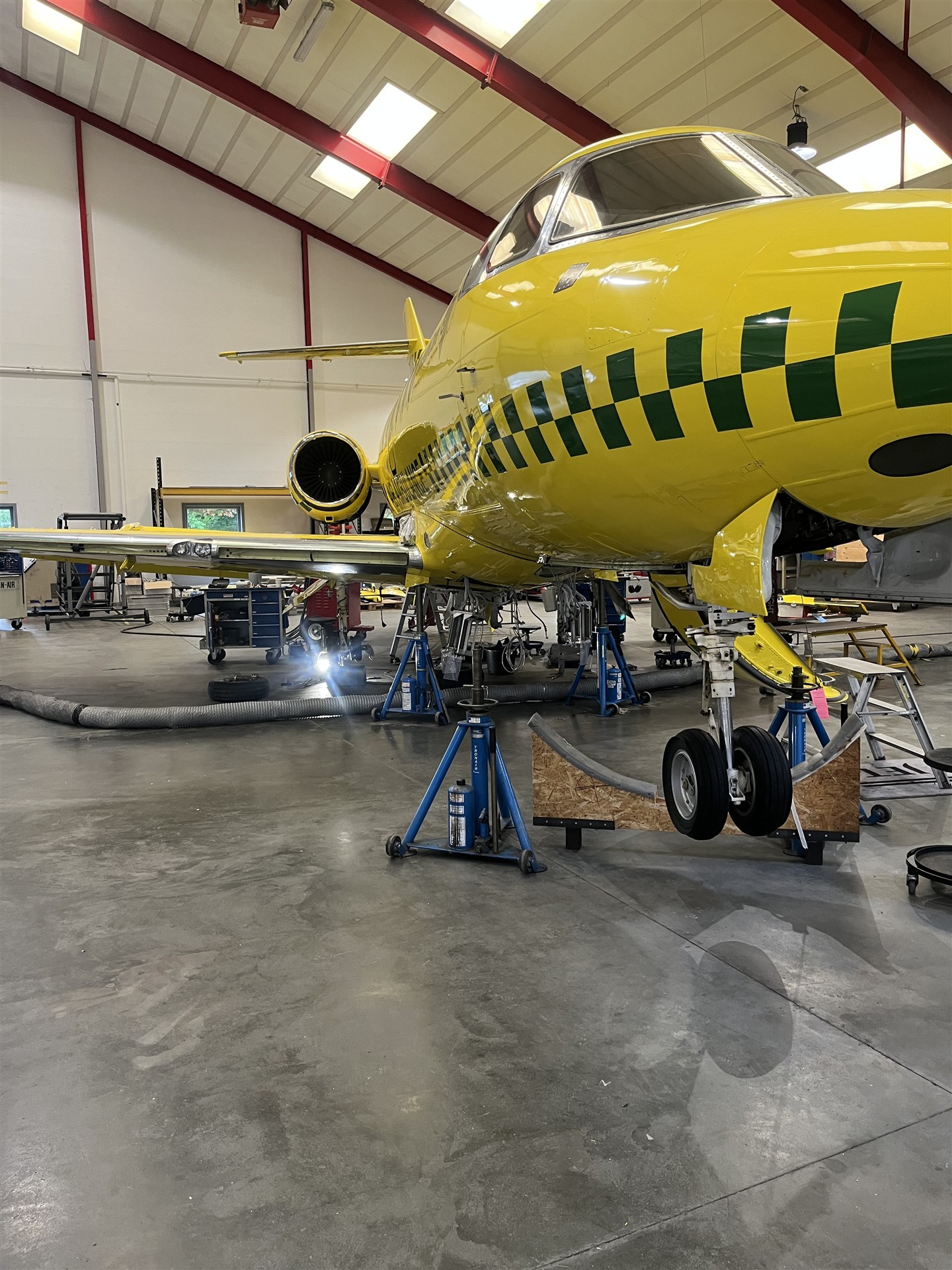 Gult fly løftet på donkrafte under vedligeholdelse i hangar