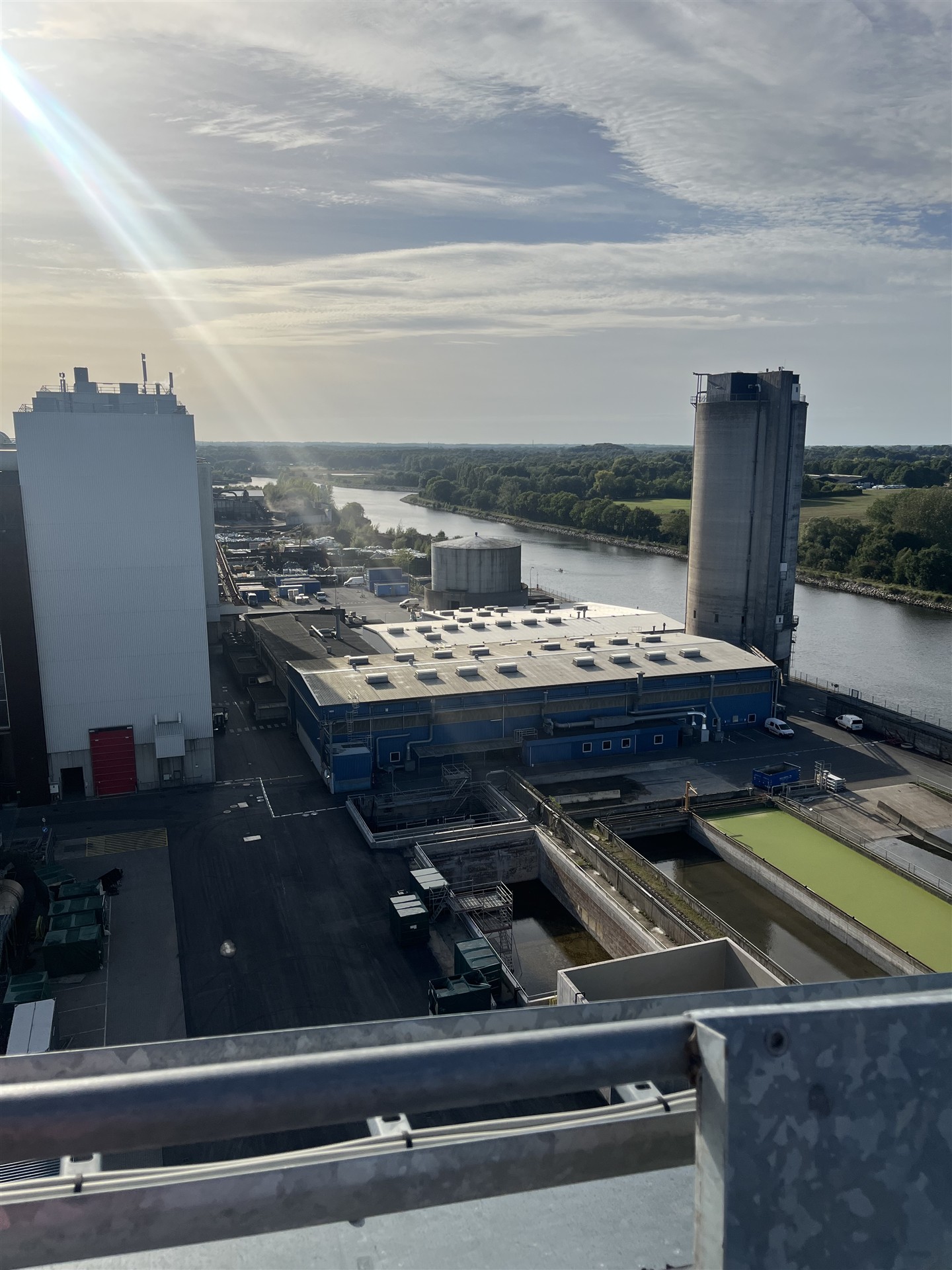 Industrianlæg med siloer og produktionsbygninger ved vandet